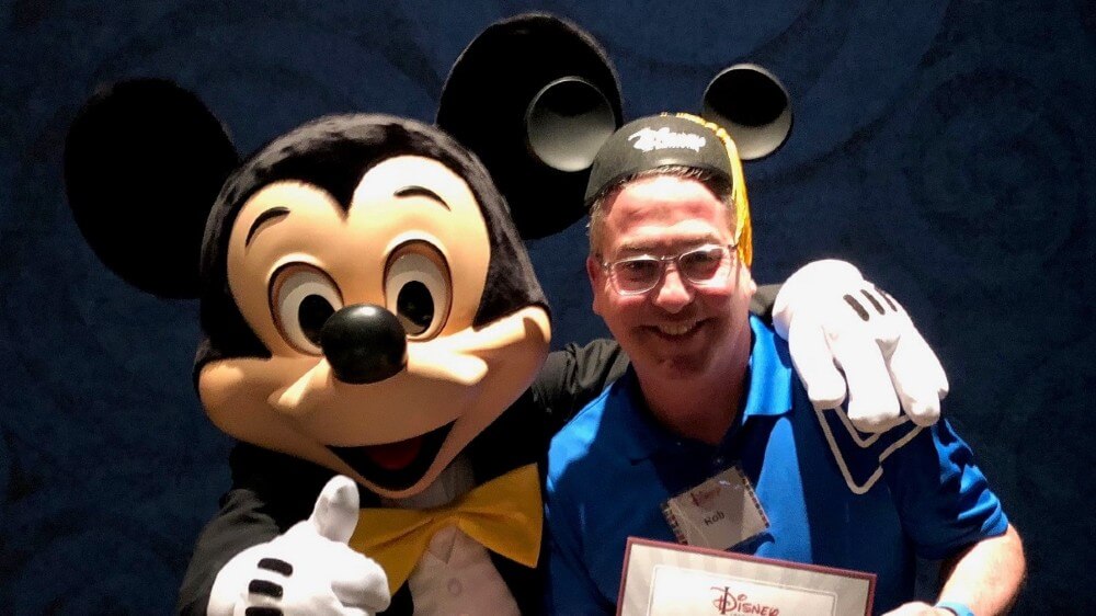 Man posing for photo with Mickey Mouse