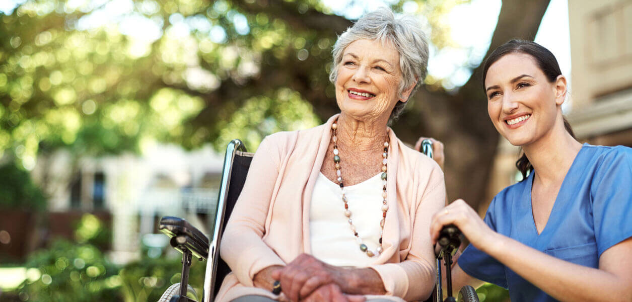 Nurse and woman in wheelchair outdoors