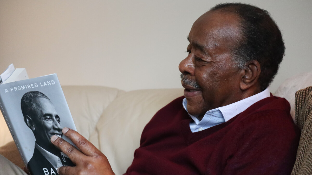 Man reading book with Barack Obama on cover