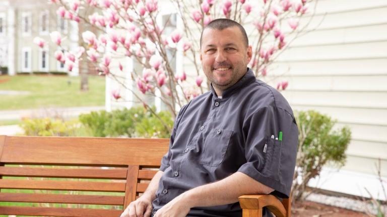 Man posing for photo on bench outdoors