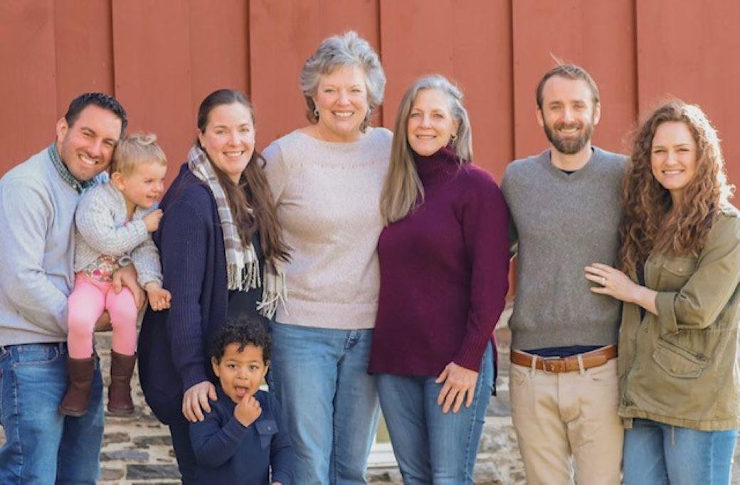 Family posing for photo outside of barn