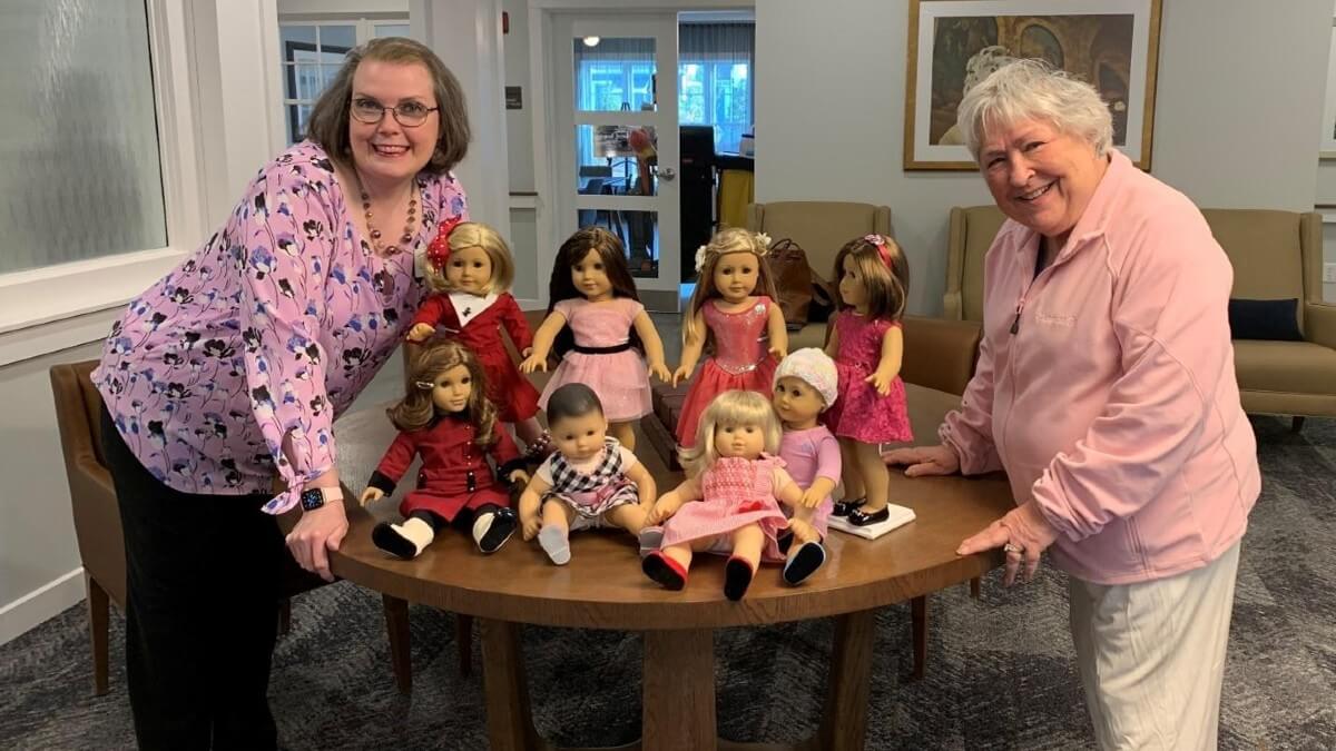 Women posing next to American Girl Dolls