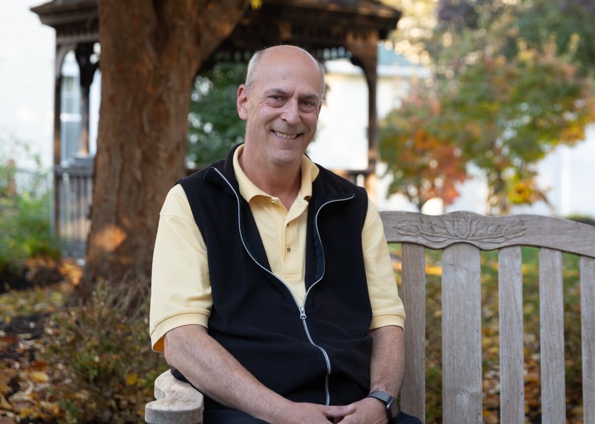 Man posing for photo on outdoor bench