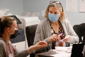 Two nurses speaking to each other wearing PPE masks