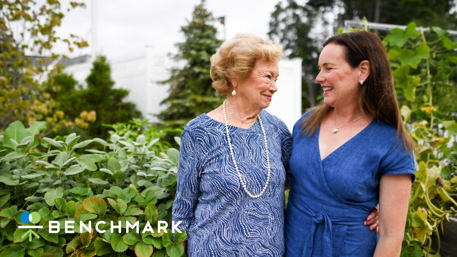 A senior woman with her arm around another woman smiling.