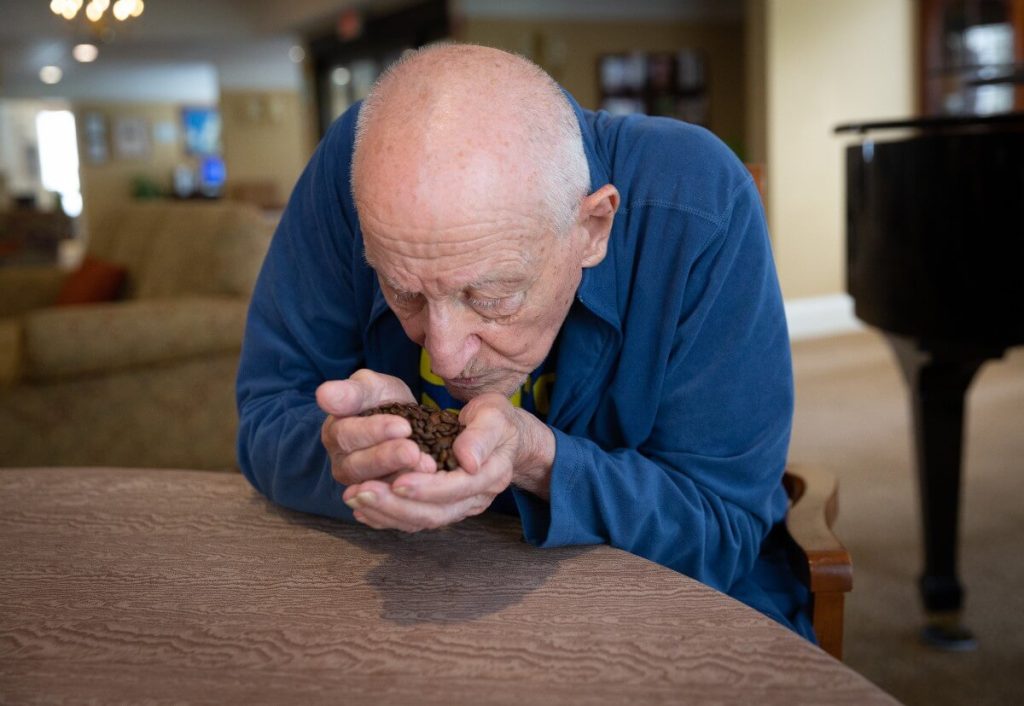 Senior man smelling coffee beans