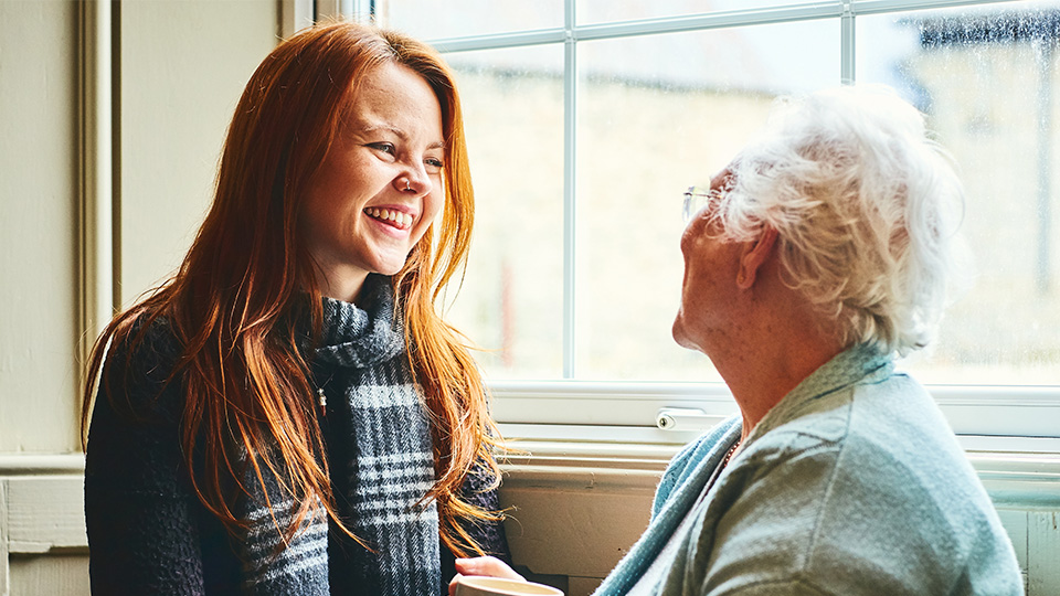 An older woman and a younger woman looking at each other and smiling