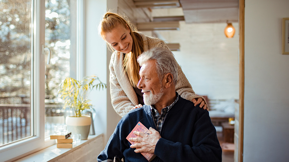 A woman with her hands on an older man's shoulders.