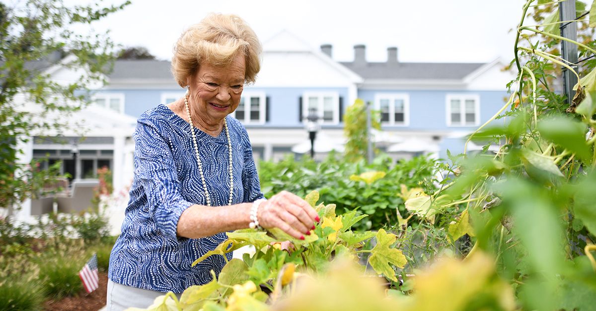 an older woman smiling working in a garden