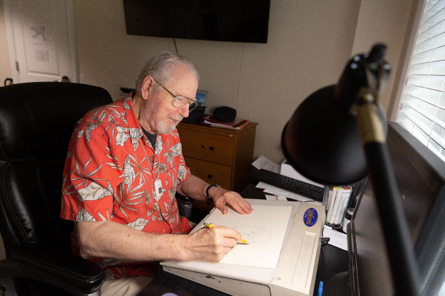Bill O'Neal drawing cartoons at a desk.