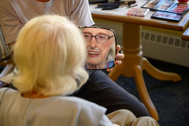 an older woman looks into a handheld mirror