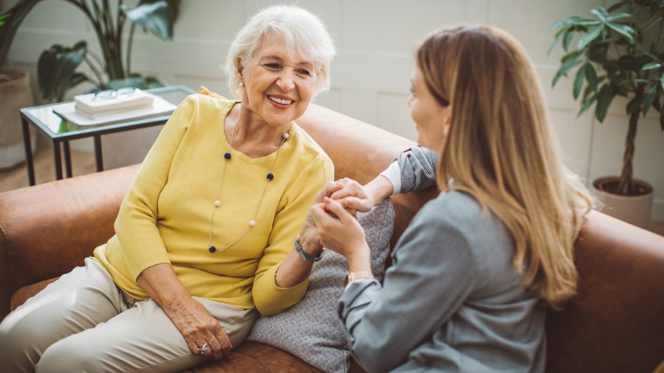 an older woman and a younger woman smiling and holding hands