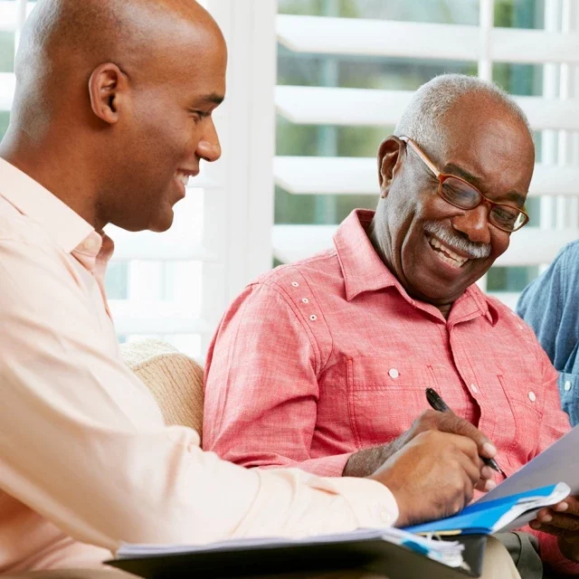 pricing_paying.jpg Man and older man signing documents
