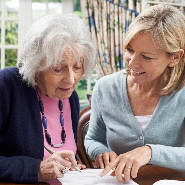 Woman and older woman signing documents