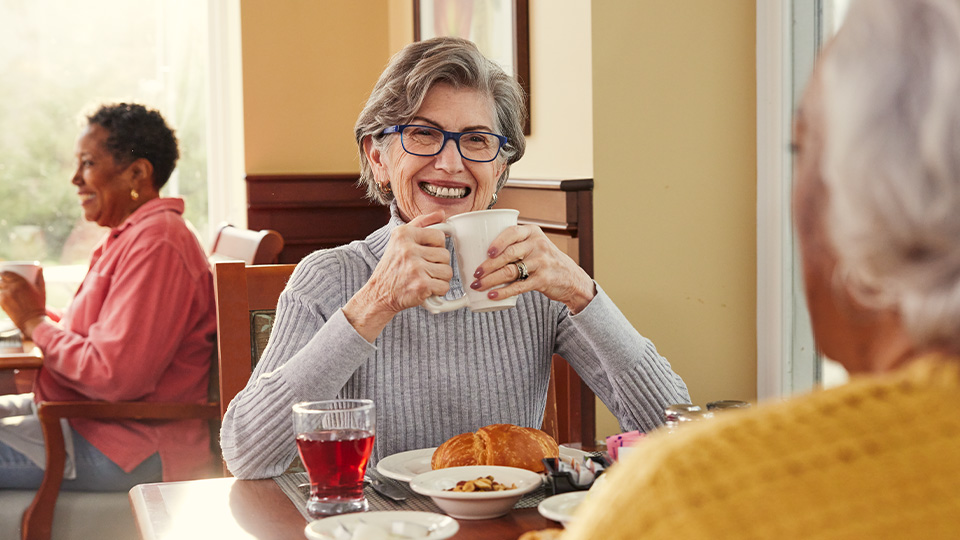 a senior holding a coffee mug and smiling