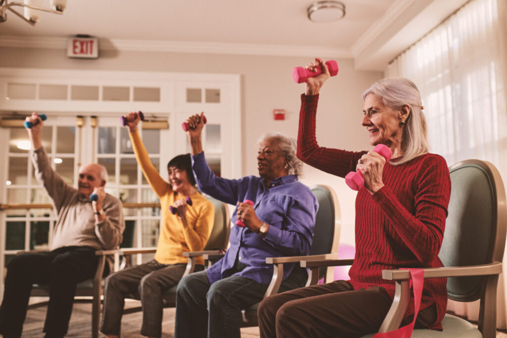 BLS_020625_Chair_Exercise_Class_2377_Condensed Senior adults participating in a group chair exercise class with hand weights at a Benchmark Senior Living community.