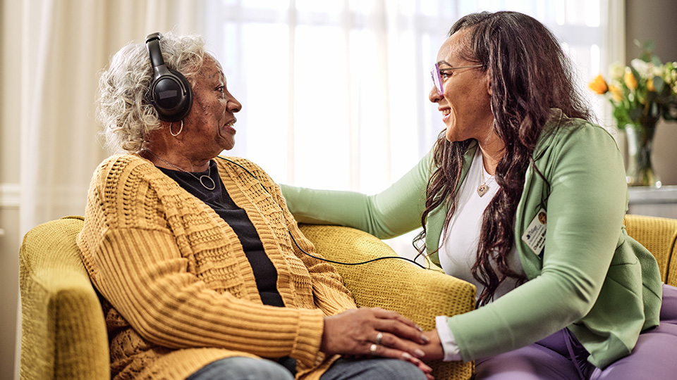 Benchmark associate smiling at a resident wearing headphones