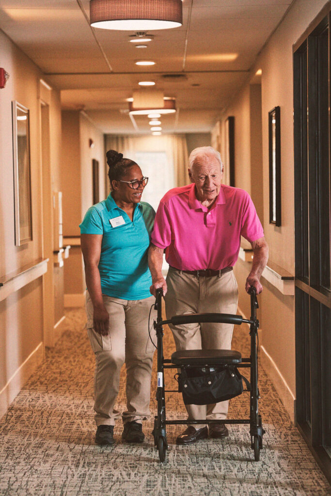An associate walking alongside a resident down a hall