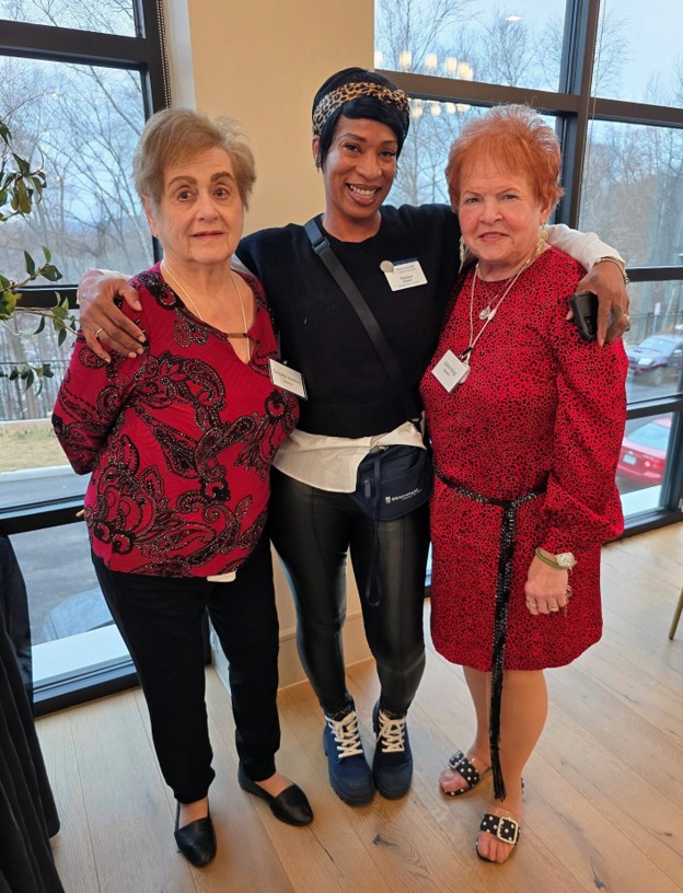 Benchmark at Mount Pleasant lead aide Tanice Hunter smiles with two residents indoors.